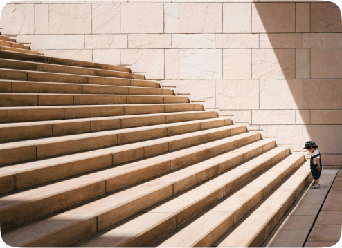 A child stares up at a beige staircase